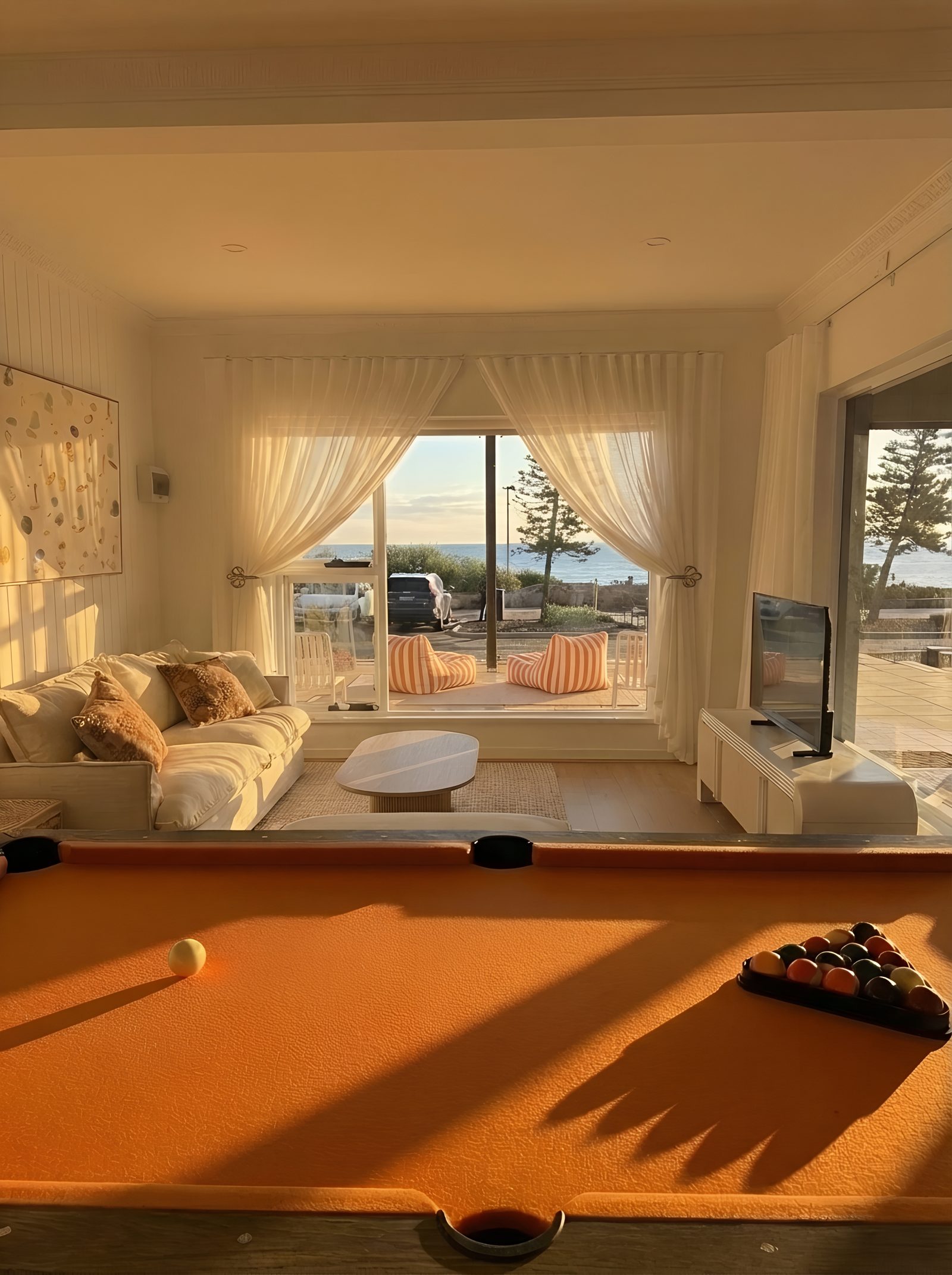 Living area at golden hour — sofa bed, pool table and ocean views
