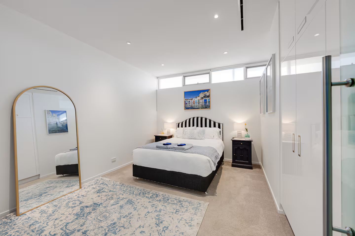 Bedroom 2 — king bed with striped headboard, gold mirror and ensuite